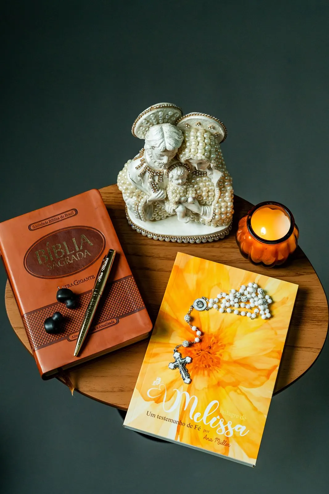 O livro com um terço, a Bíblia e uma vela acesa